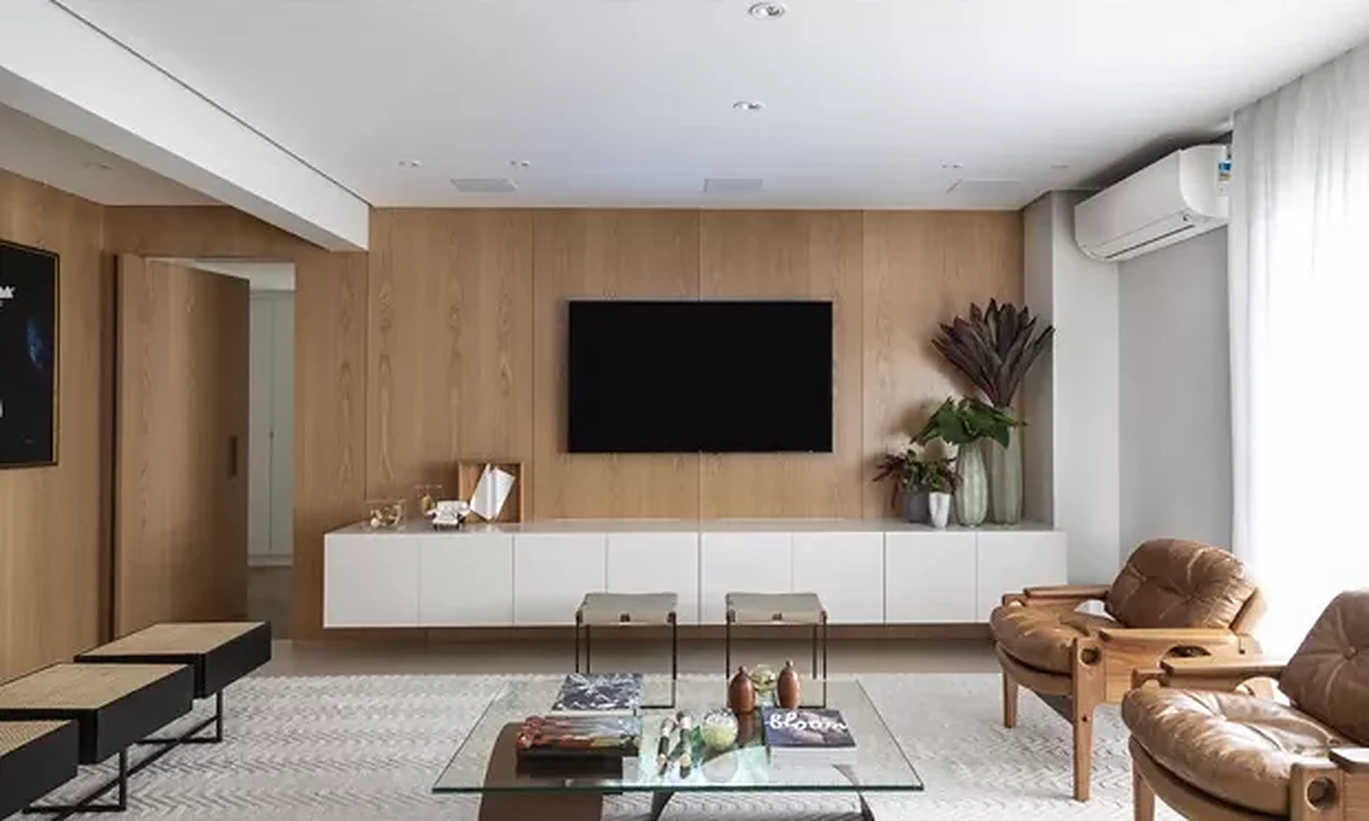 Depois: living com painel de madeira, rack branco e poltronas de couro